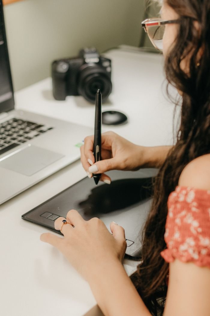 Mastering the First Impression: Your intriguing post title goes here Female graphic designer working with a tablet and laptop in a modern workspace.
